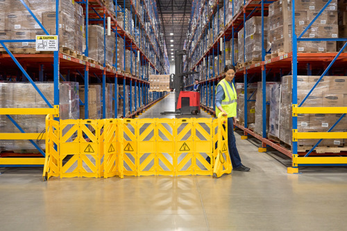 Rubbermaid mobile barrier fully extended in a warehouse, marking off a restricted area for enhanced safety