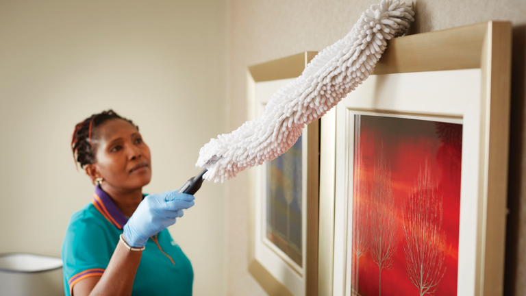 Housekeeper Cleaning a Wall Frame