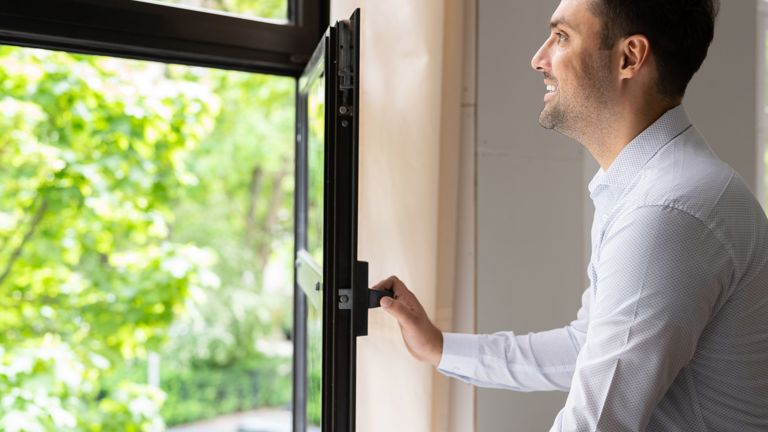 A man opening a window for fresh air