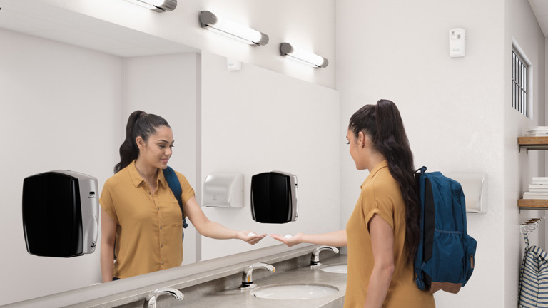 Image of a woman getting soap from Rubbermaid AUTOFOAM DISPENSER