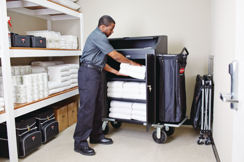 Housekeeping staff organising towels on Rubbermaid cart