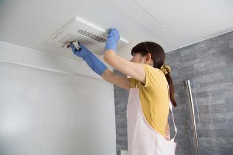 A woman cleaning a ceiling vent