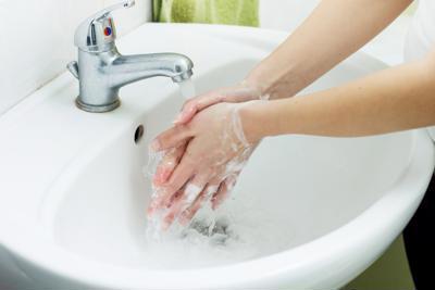A person washing their hands in the sink with soapy water