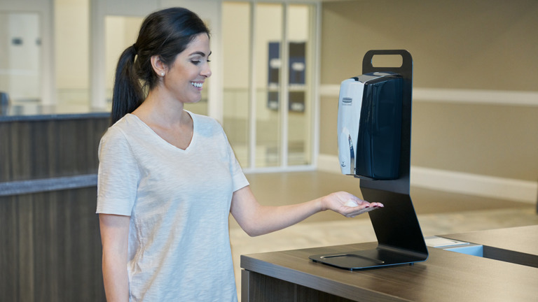 Woman using Rubbermaid Commercial Tabletop Stand Dispenser