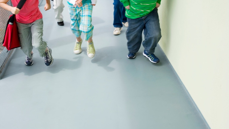 A gray school hallway with vinyl flooring